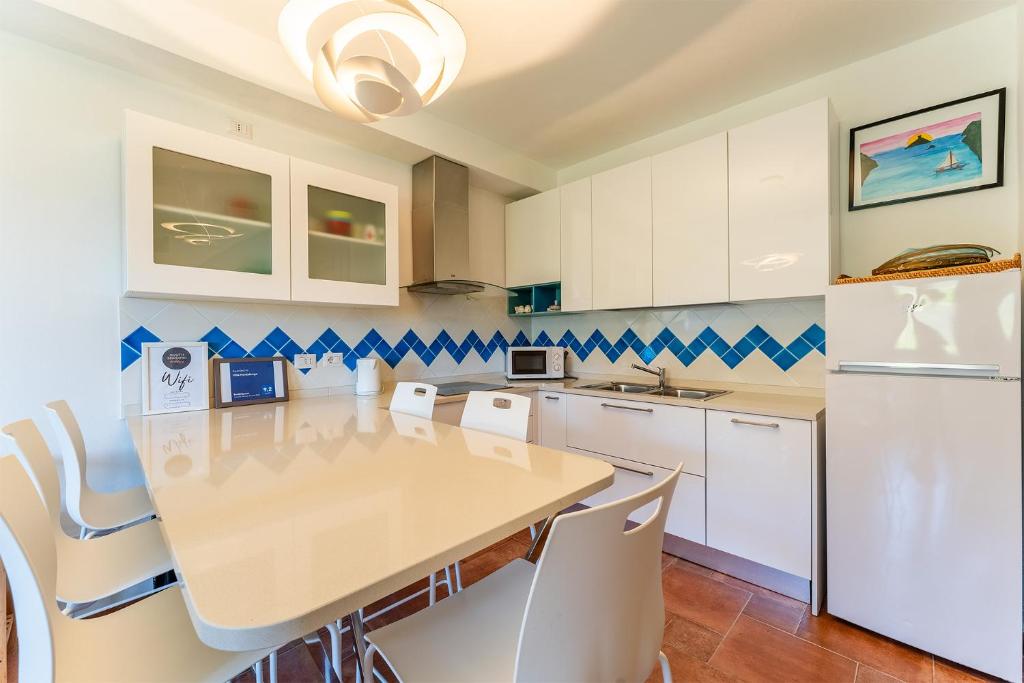 a kitchen with a table and white cabinets at Villa Perdalonga, Vista Mare Sea View Tuerredda in Teulada