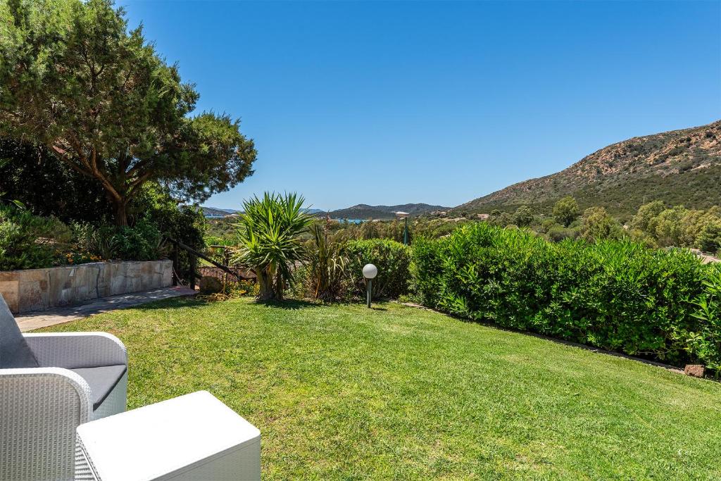 a garden with a lawn and trees and mountains at Villa Perdalonga, Vista Mare Sea View Tuerredda in Teulada