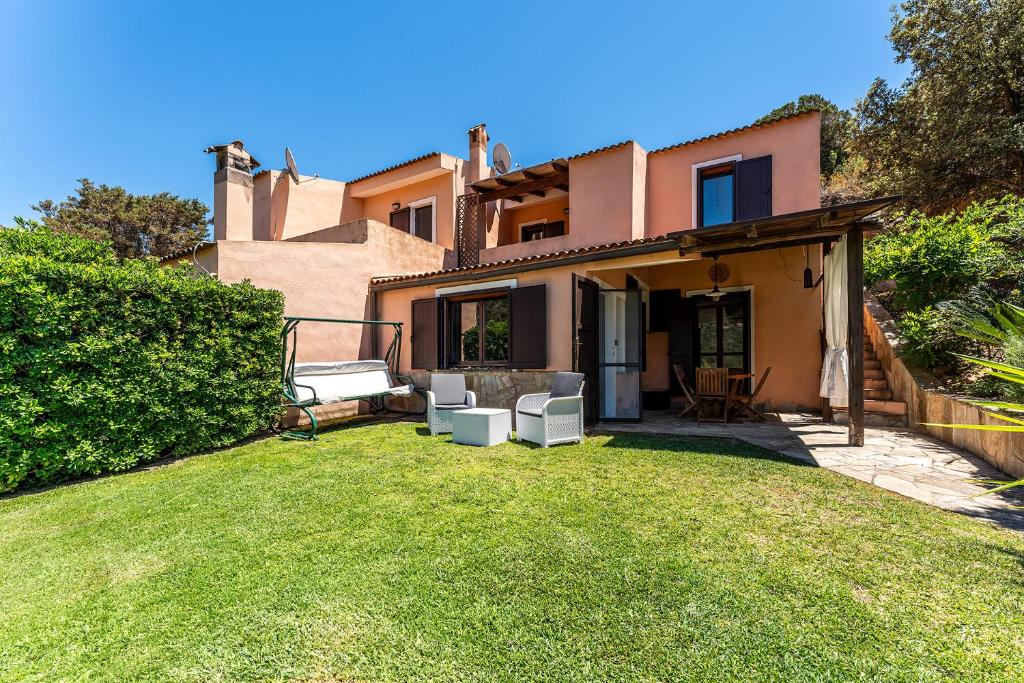 a house with a yard with two lawn chairs at Villa Perdalonga, Vista Mare Sea View Tuerredda in Teulada
