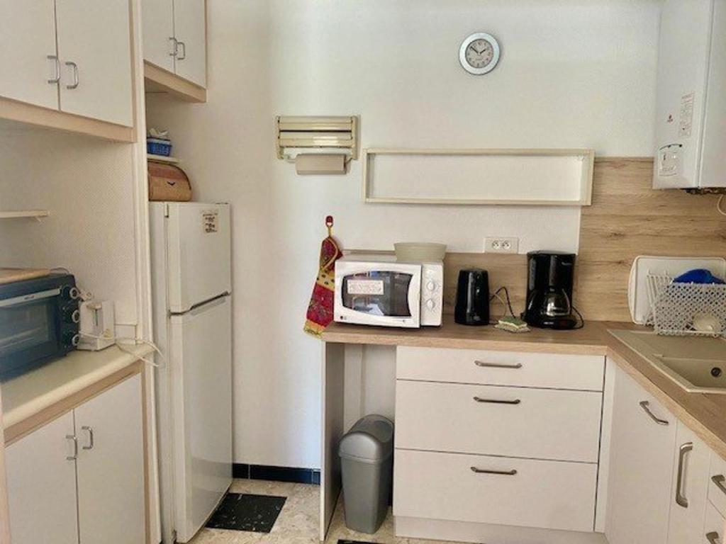 małą kuchnię z białymi szafkami i kuchenką mikrofalową w obiekcie Studio cosy avec terrasse, parking et wifi - Idéal cures et centre-ville, Amélie-les-Bains - FR-1-703-3 w mieście Amélie-les-Bains-Palalda