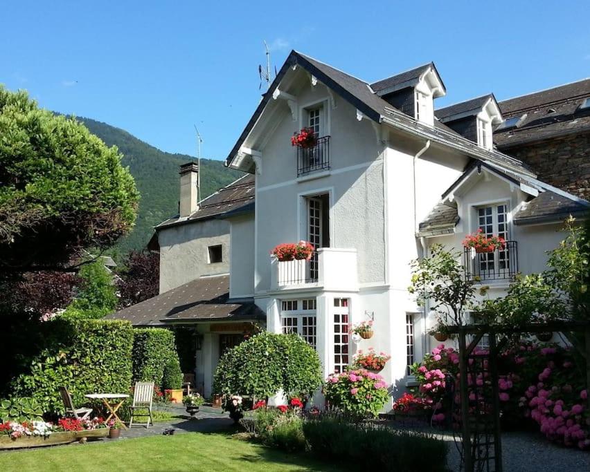 una casa bianca con fiori in un cortile di Villa Portillon - charming fountain garden villa a Luchon