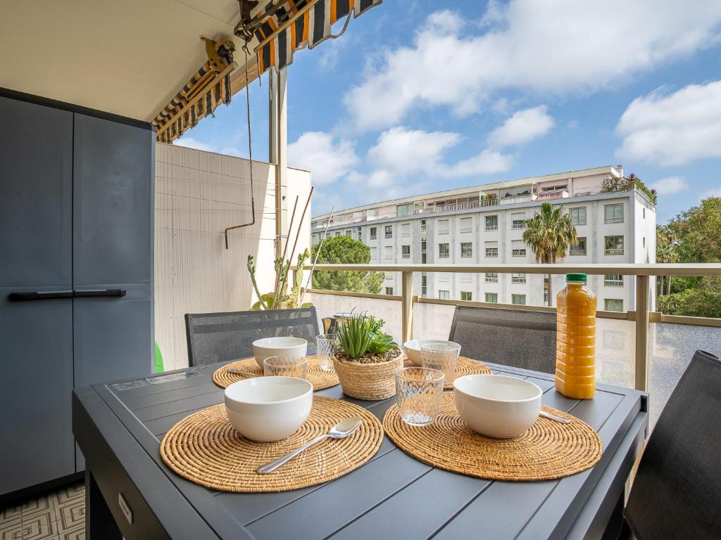 une table avec des bols et des assiettes sur un balcon dans l'établissement Apartment Les Aliscamps by Interhome, à Cannes