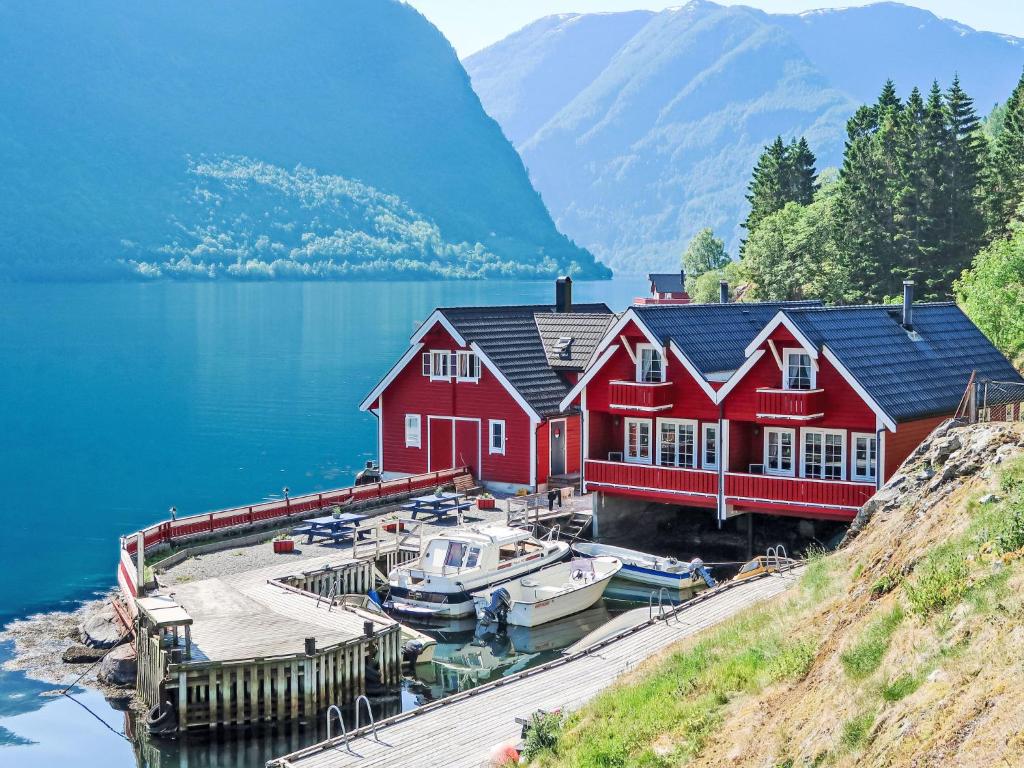 a red house on a dock with boats in the water at Holiday Home Jambueggi by Interhome in Arnefjord