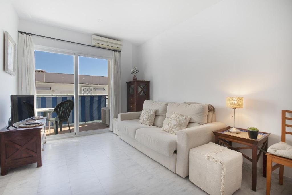 ein Wohnzimmer mit einem weißen Sofa und einem Fernseher in der Unterkunft Plata Ático in Torremolinos