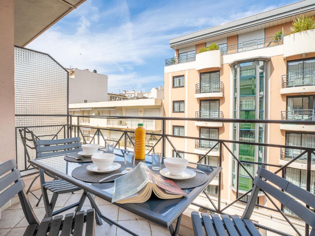 une table et des chaises sur un balcon avec vue sur un immeuble dans l'établissement Apartment Le Cheverny by Interhome, à Cannes