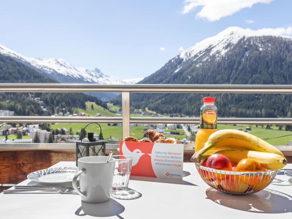 a bowl of fruit on a table with a view of mountains at Apartment Guardaval - Utoring-66 by Interhome in Davos