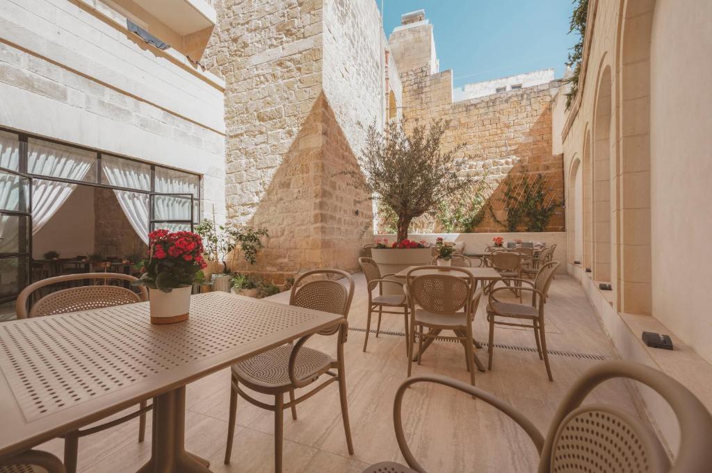 an outdoor patio with tables and chairs and windows at Maria Rosa Suites in Victoria