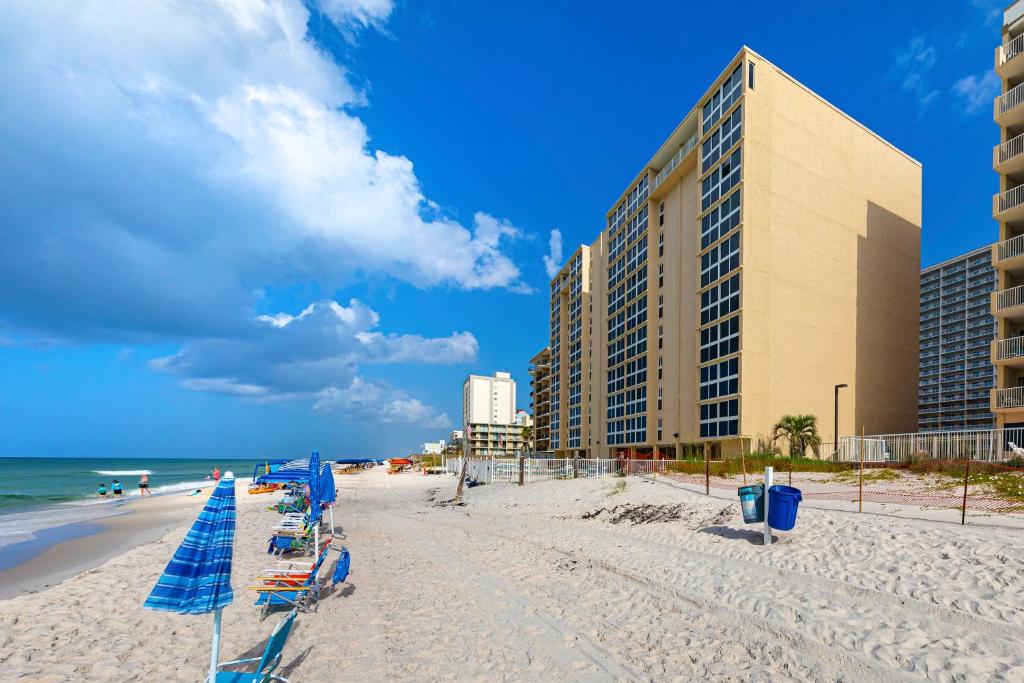 a beach with blue beach chairs and a building at Edgewater West Condos in Gulf Shores
