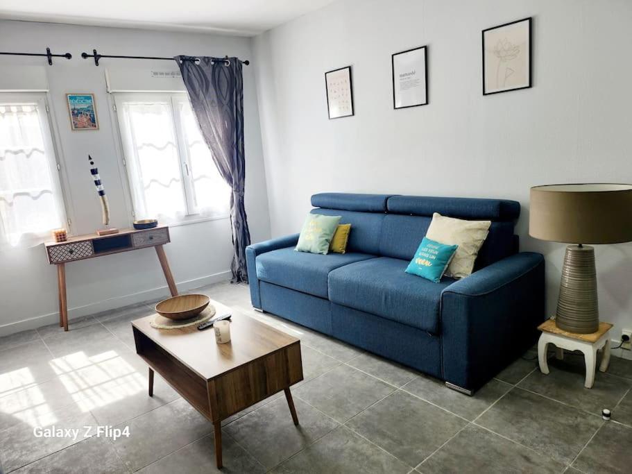 un salon avec un canapé bleu et une table dans l'établissement le Côme-ci, comme ça, à Fécamp