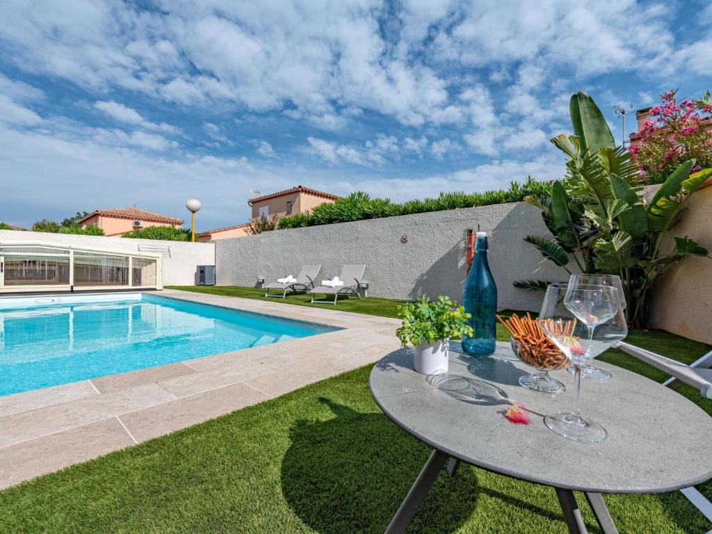 patio con tavolo e bicchieri da vino accanto alla piscina di Villa Ladine by Interhome a Le Barcarès