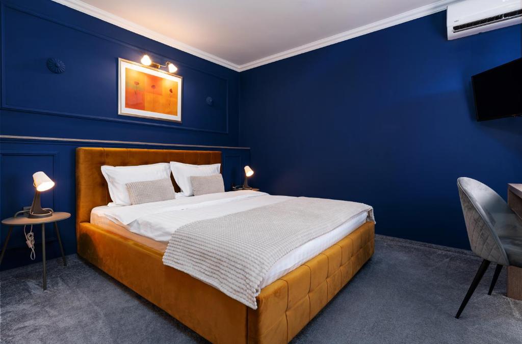 a blue bedroom with a bed and a blue wall at Hotel Cocó in Timişoara