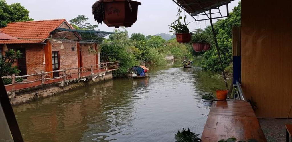 a view of a river with a house and a boat at Tam Coc Paradise Homestay in Ninh Binh