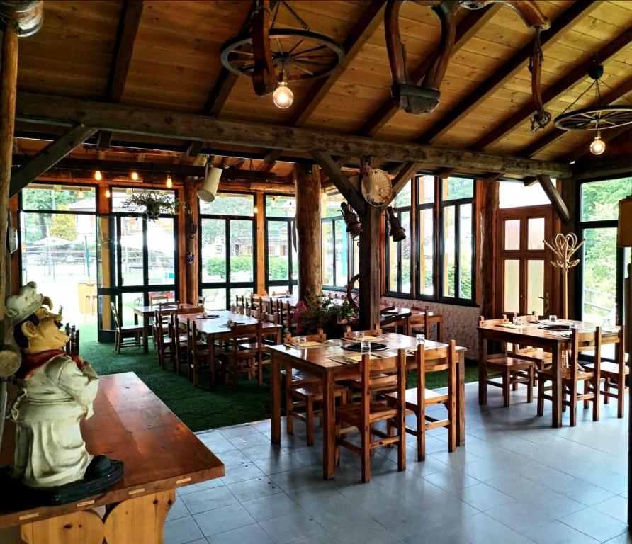restauracja z drewnianymi stołami, krzesłami i oknami w obiekcie Green Riviera Case Vacanza w mieście Borzonasca