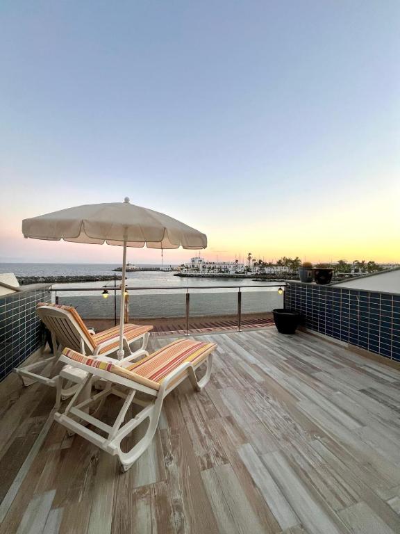 two lounge chairs and an umbrella on a deck at COSTA AZUL APARTMENTS - 1C in Puerto de Mogán