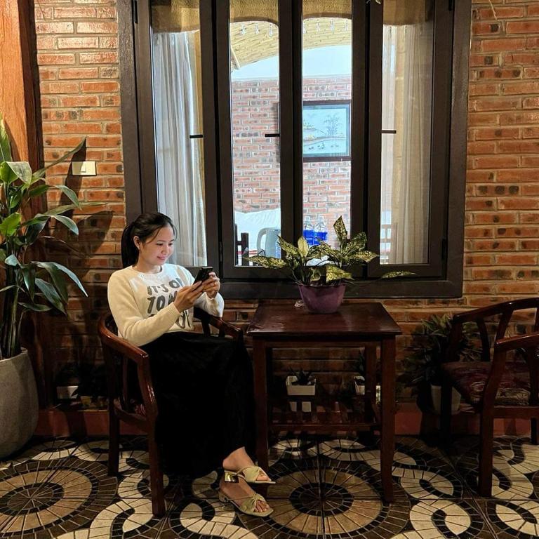 a woman sitting in a chair looking at her cell phone at Tam Coc Paradise Homestay in Ninh Binh