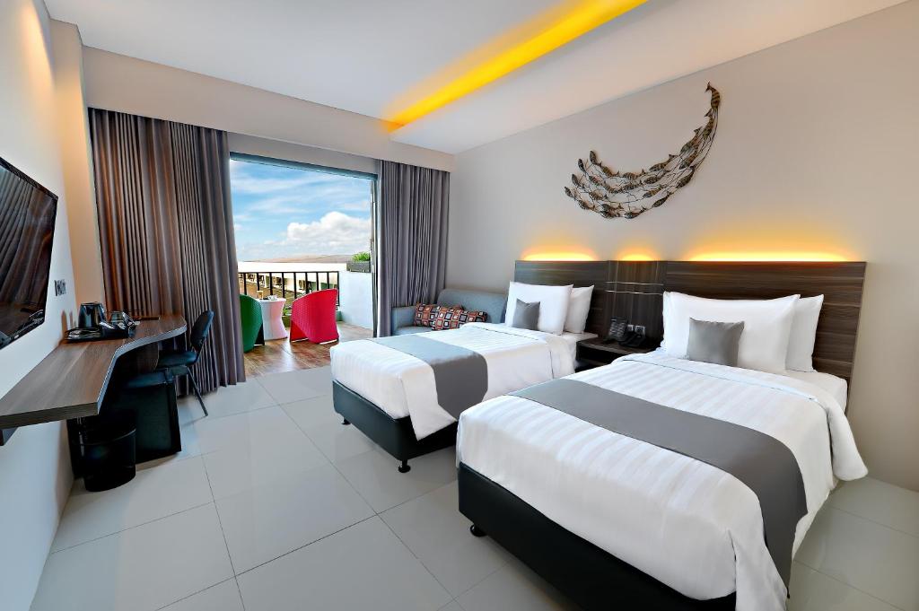 a hotel room with two beds and a television at Neo Eltari Kupang by ASTON in Kupang