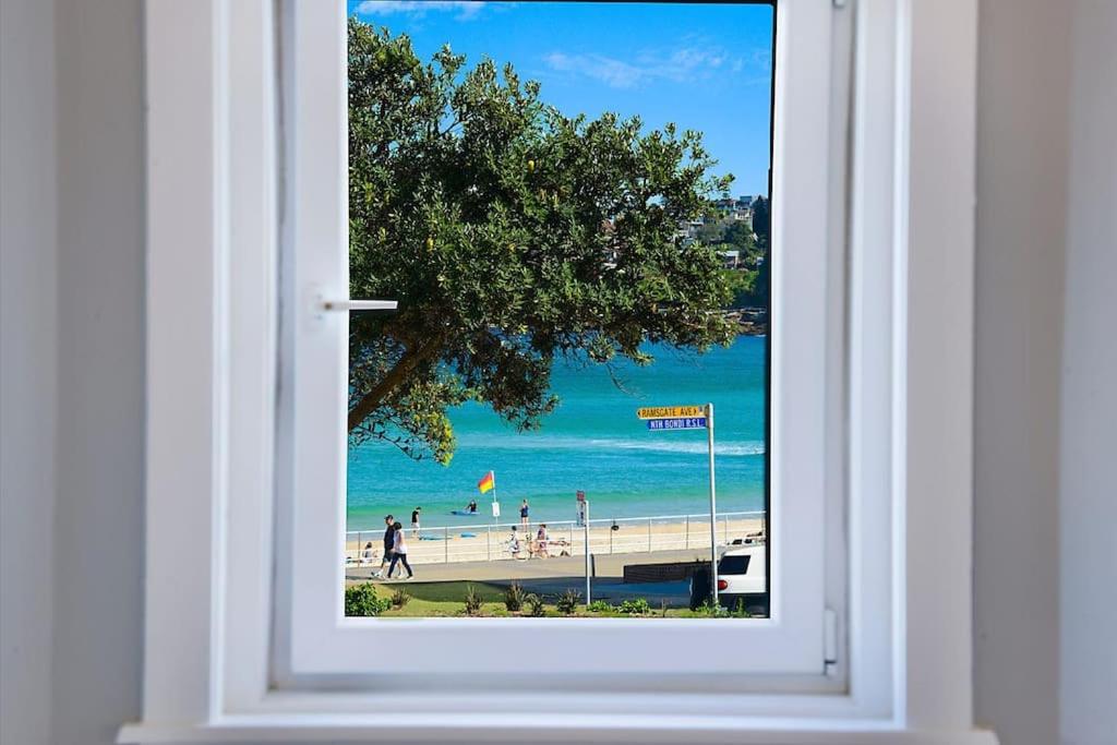 a view of a beach through a window at Beachside Boho Retreat by Sydney Dreams in Sydney