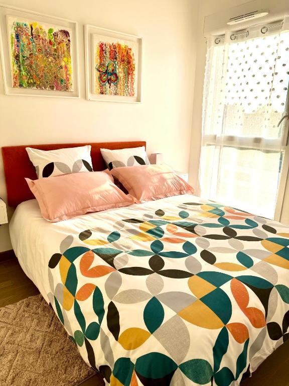 - un lit avec une couette colorée dans une chambre dans l'établissement ROMARIN-Gares, à Lille