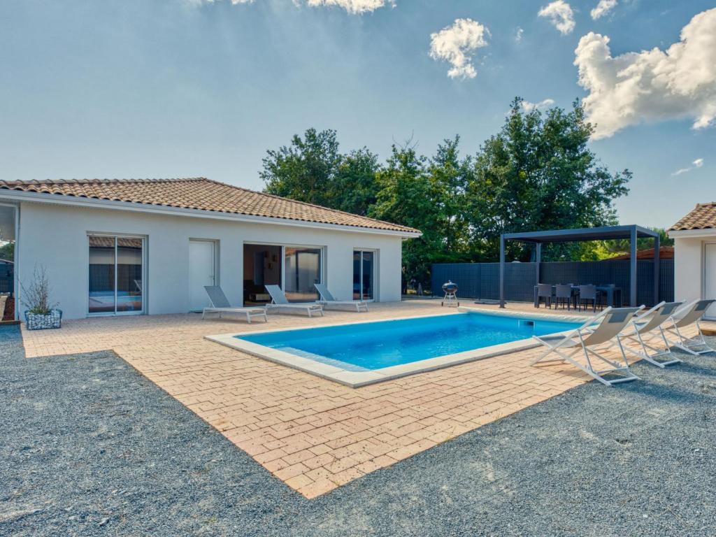 une piscine avec des chaises et une maison dans l'établissement Villa Les Tamaris by Interhome, à Vendays-Montalivet
