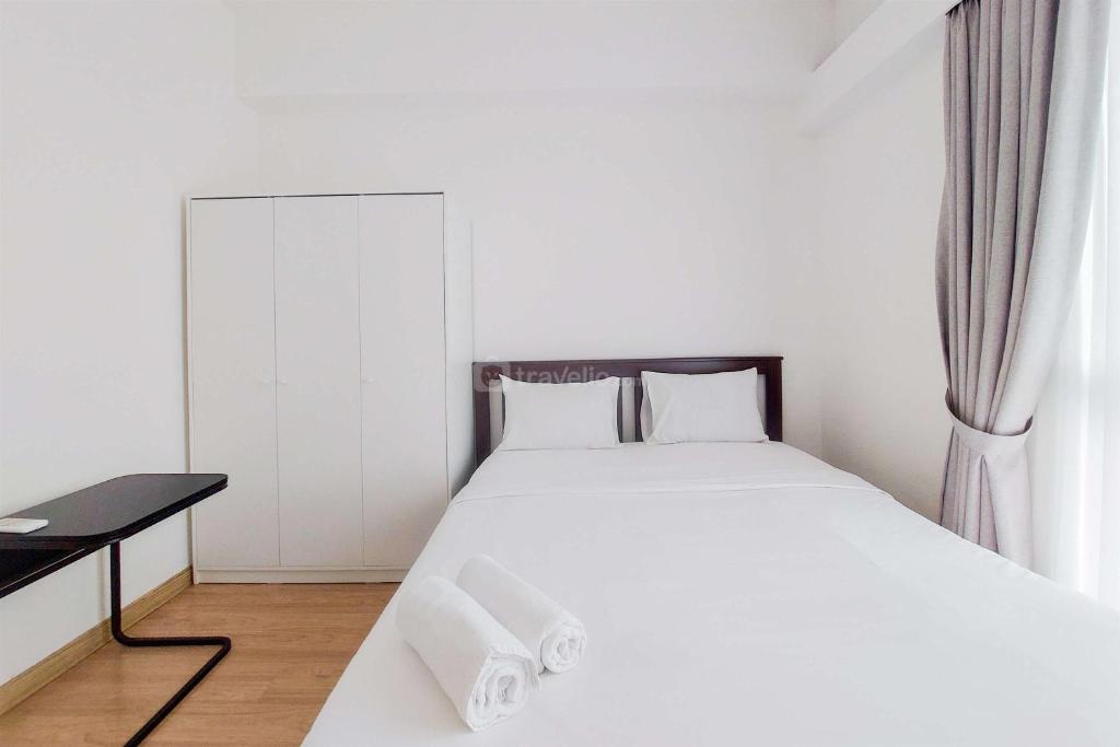 a bedroom with a white bed and a desk at Spacious and Cozy 3BR Sky House BSD Apartment By Travelio in Tangerang