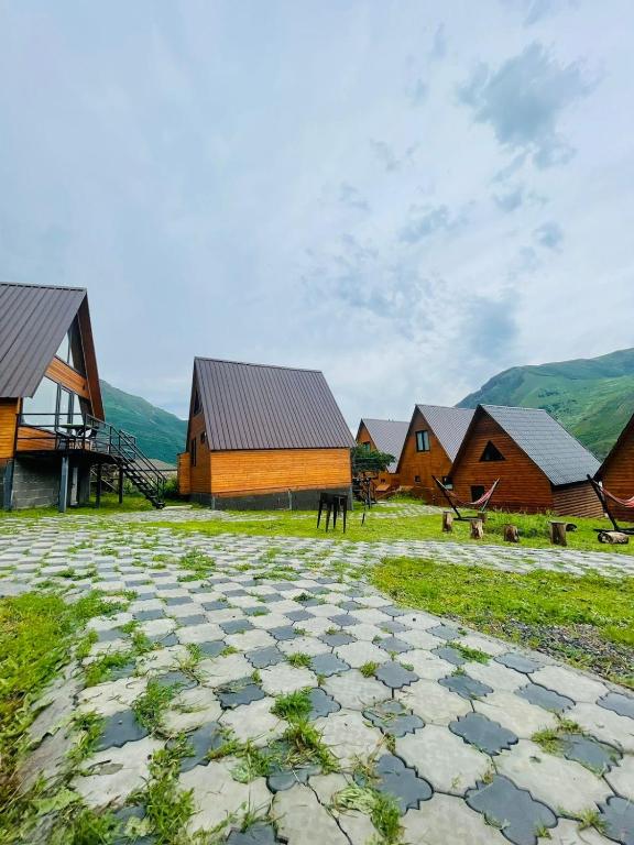 un gruppo di edifici con montagne sullo sfondo di Guesthouse Elli & Cottages a Kazbegi