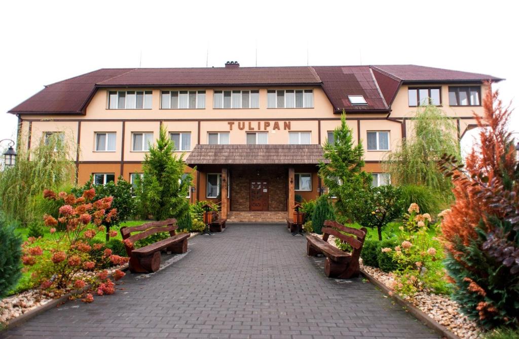 a hotel with benches in front of a building at Tulipan Hotel Aquapark in Vyshkove