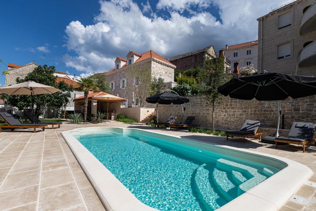 una piscina con ombrelloni accanto a un edificio di Grand Stone Casa Ciccarelli by Irundo a Pučišća