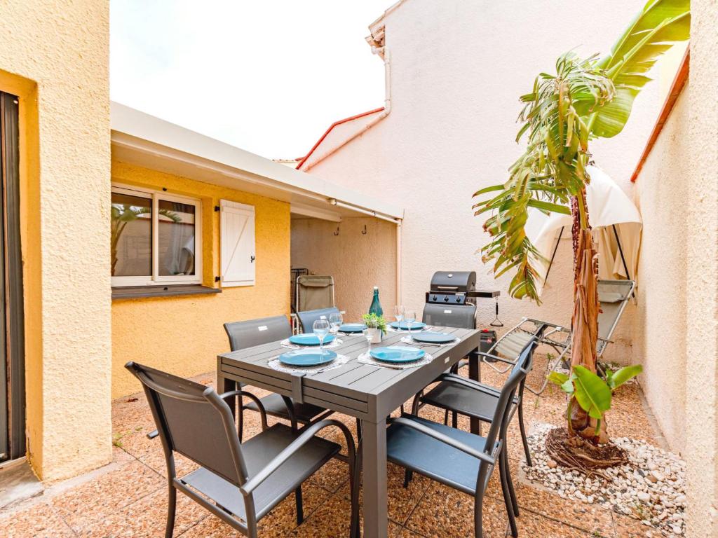 un patio avec une table, des chaises et un palmier dans l'établissement Apartment Zodiaques 2-5 by Interhome, au Barcarès