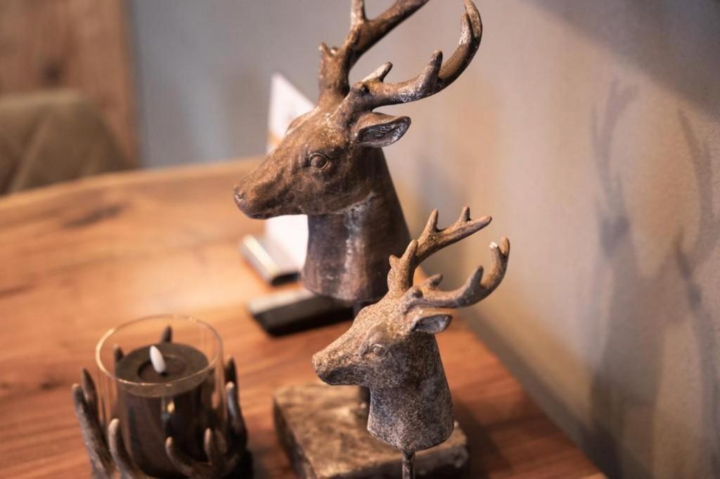 deux statues de cerfs sur une table en bois avec une bougie dans l'établissement Schöneben Appartementen Top 4, à Wald im Pinzgau