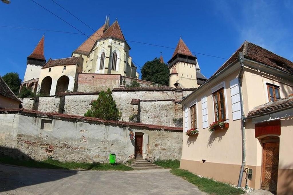 ein altes Gebäude mit einem Schloss im Hintergrund in der Unterkunft Pensiunea Oppidum in Biertan