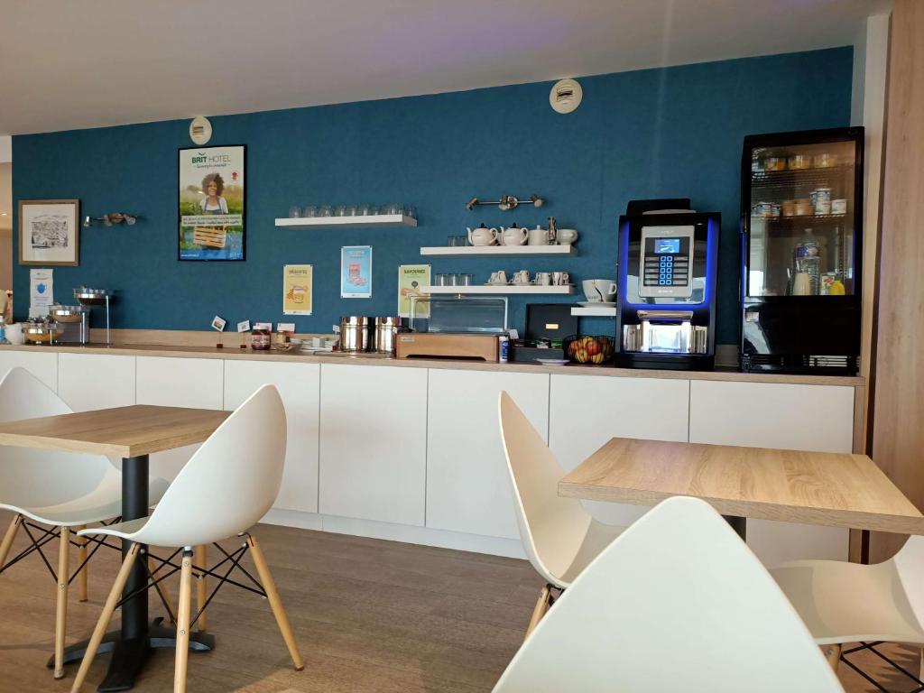 a restaurant with a counter with chairs and a table at Brit Hotel Les Alizes in Pornic