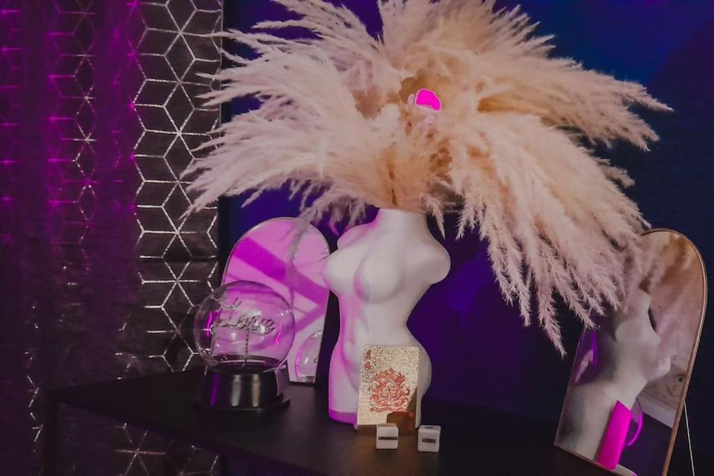 une statue d'un mannequin avec un grand chapeau à plumes dans l'établissement Suite Jeux Coquins La Curieuse, à Villersexel