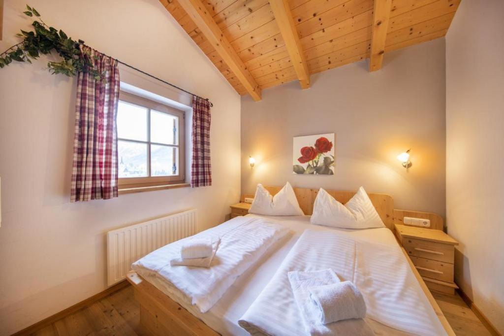 a bedroom with a large white bed with a window at Schöneben Chalet MilKa in Wald im Pinzgau