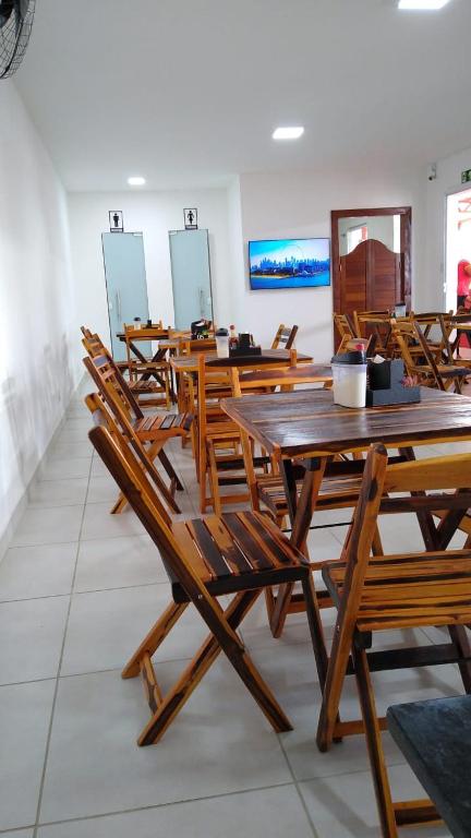 un grupo de mesas y sillas de madera en una habitación en Pousada e Restaurante Br101, en Santo Antônio de Jesus