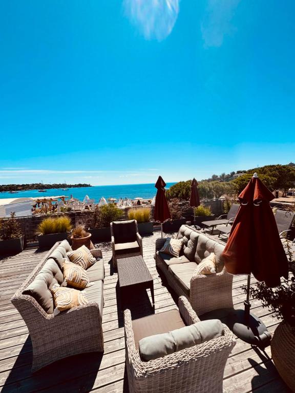 un patio avec des canapés et des parasols et la plage dans l'établissement Magnifique Appartement Climatisé Vue Mer Ref LA PLAGE, à Agay