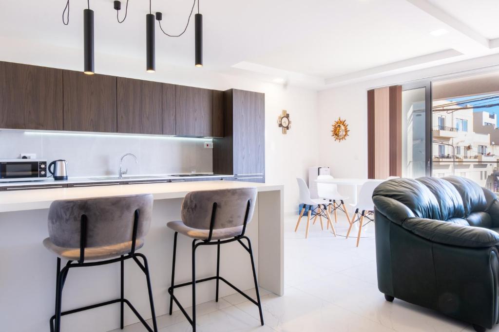 a kitchen with a counter and two bar stools at Mellieha, Charming 2 Bedroom Apartment Santa Maria Heights Mellieha in Mellieħa