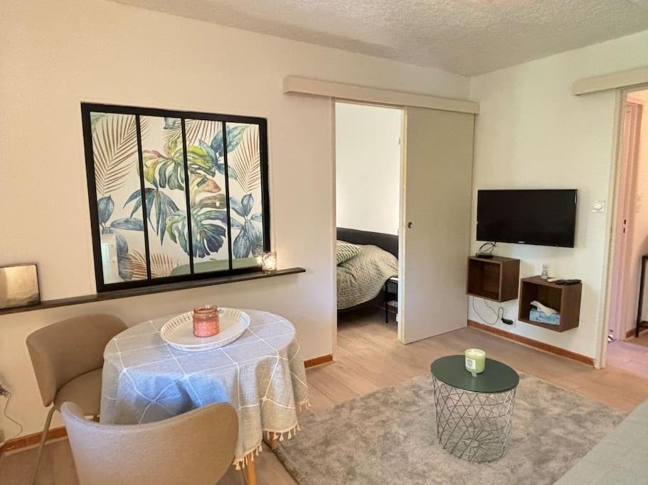 un salon avec une table et une télévision dans l'établissement L Aurore T2, à Aix-en-Provence