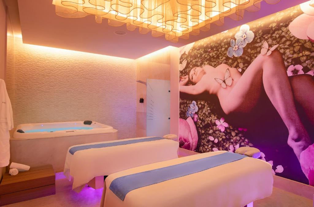 a room with two beds and a painting on the wall at Desire Riviera Maya Resort All Inclusive - Couples Only in Puerto Morelos