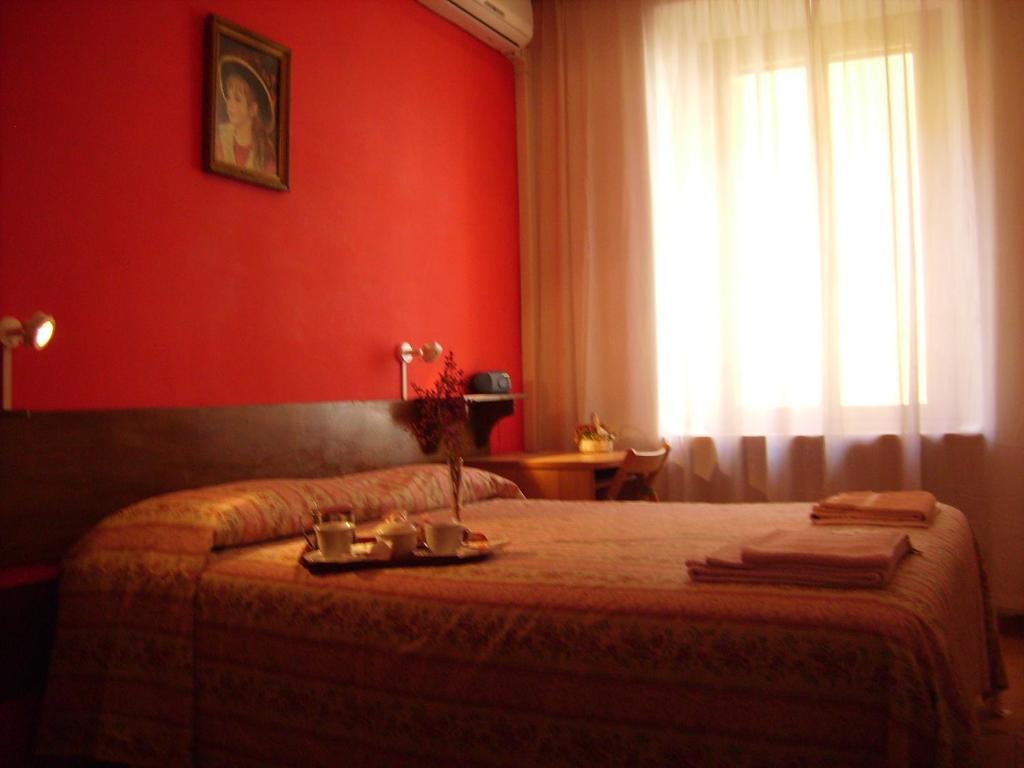 ローマにあるB&B Vaticanroomsのベッドルーム1室(赤い壁のベッド1台、窓付)