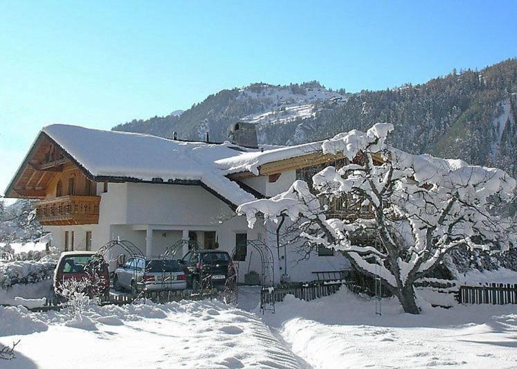 ein schneebedecktes Haus mit davor geparkt in der Unterkunft Apart Daniel in Ried im Oberinntal