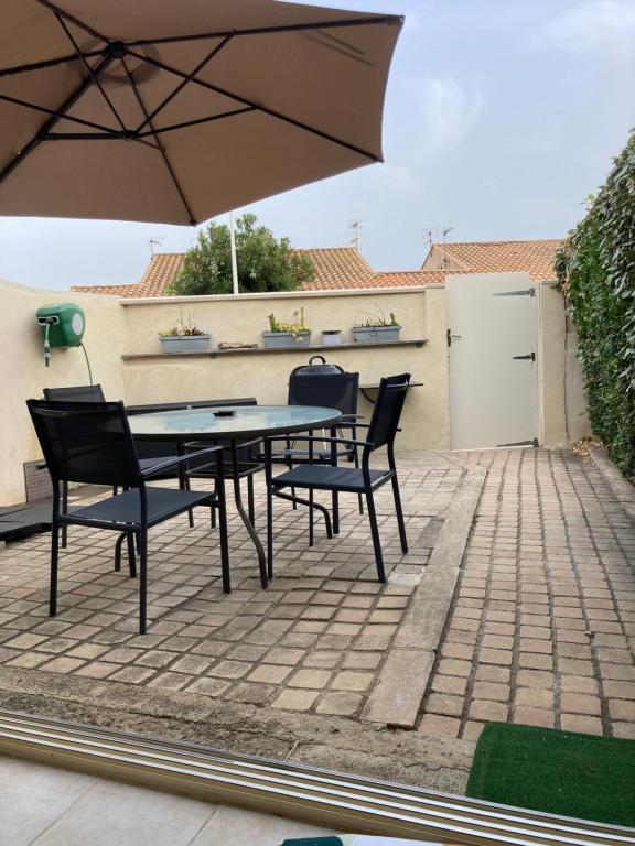 une table et des chaises avec un parasol sur une terrasse dans l'établissement Maison du rivage bleu, à Gruissan