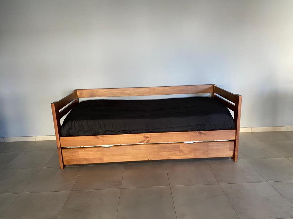 a wooden bed sitting against a white wall at El Quincho in Lobos