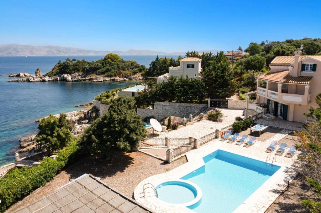 een huis met een zwembad naast het water bij Villa Angelos by Villa Plus in Kassiopi