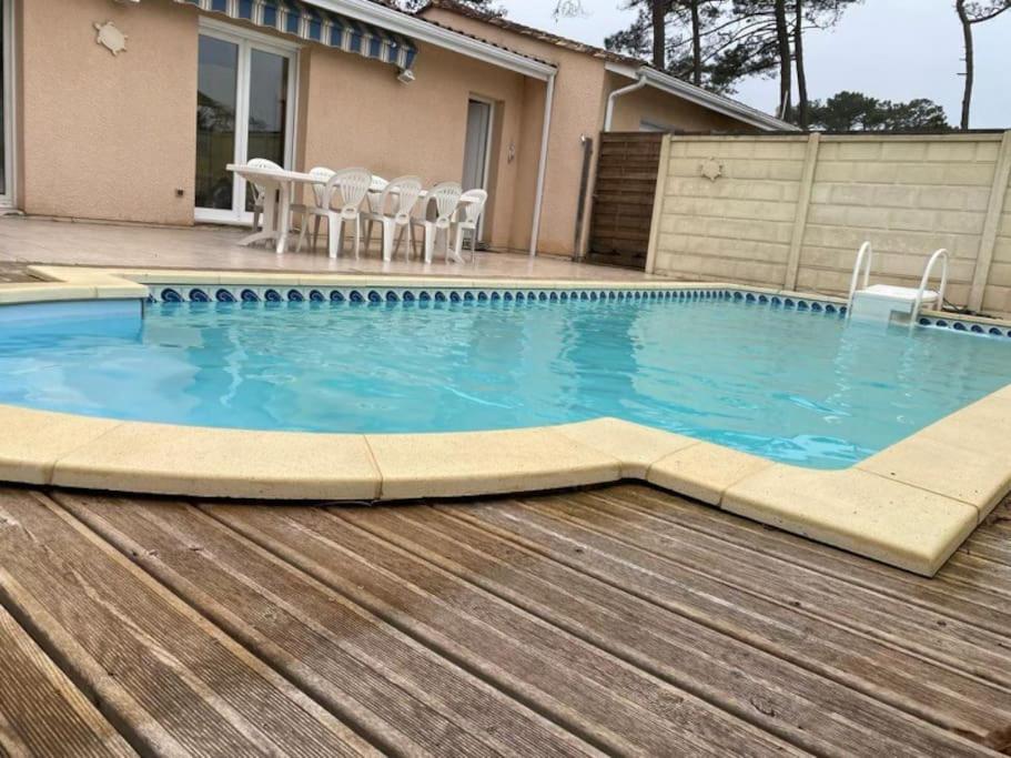 - une piscine avec une table et des chaises dans l'établissement Villa proche océan à Montalivet les Bains, à Vendays-Montalivet