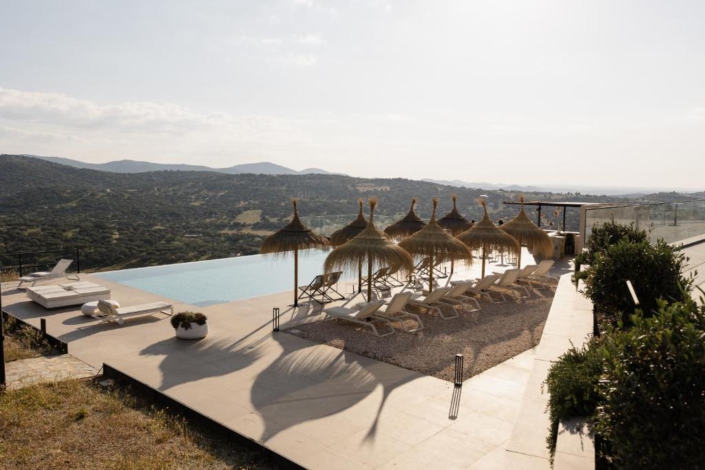 una piscina con sillas y sombrillas y una piscina en Hoteles Desconecta2, en Monesterio
