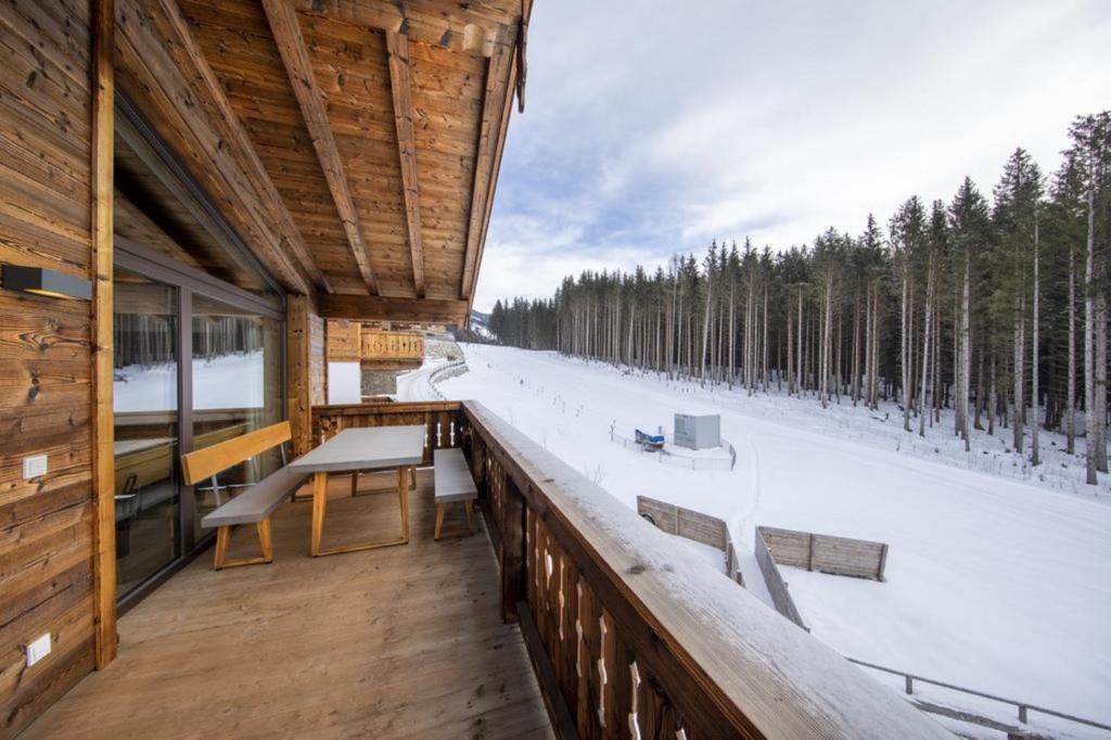 a balcony of a cabin with a table and benches at Nationalpark Chalet Säulspitze in Neukirchen am Großvenediger