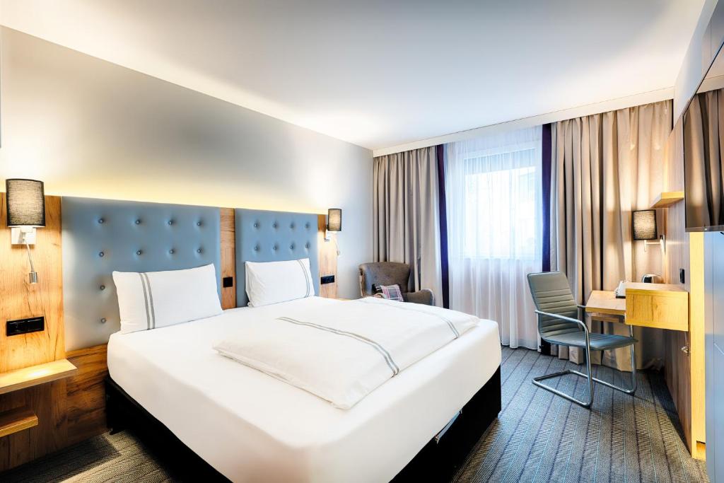 Una habitación de hotel con una cama grande y un escritorio. en Premier Inn Lindau, en Lindau