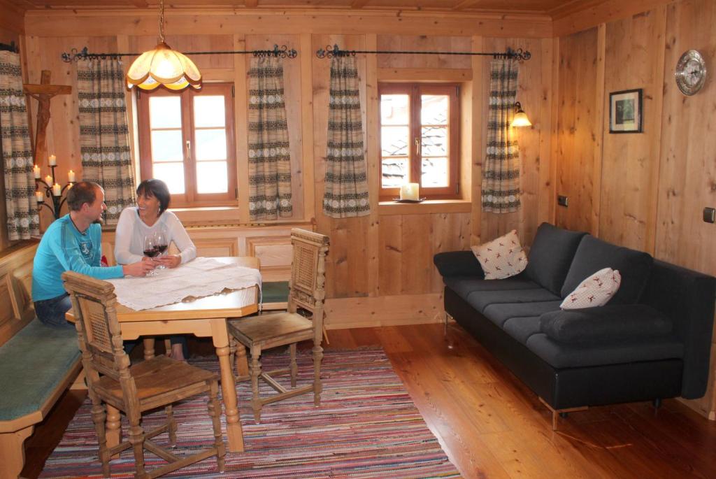 two people sitting at a table in a living room at Ferienhaus Veider in Obertilliach