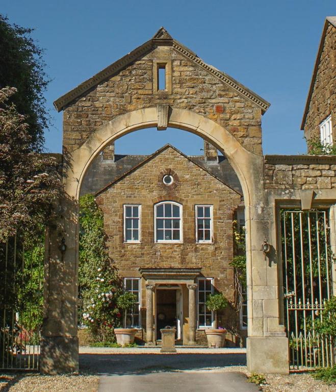 a stone house with an archway in front of a gate at West Compton Manor in Dorchester