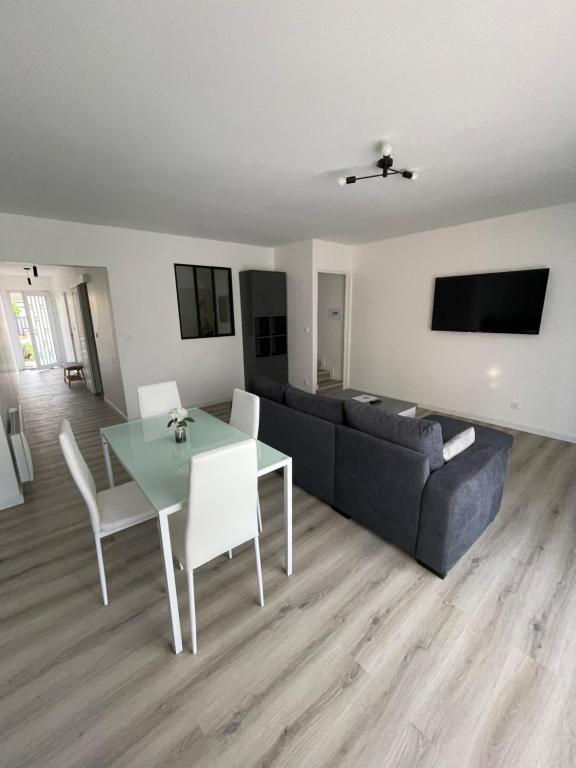una sala de estar con un sofá y una mesa en Maison 100m2 uniquement famille, couple & professionnel, en Villeparisis